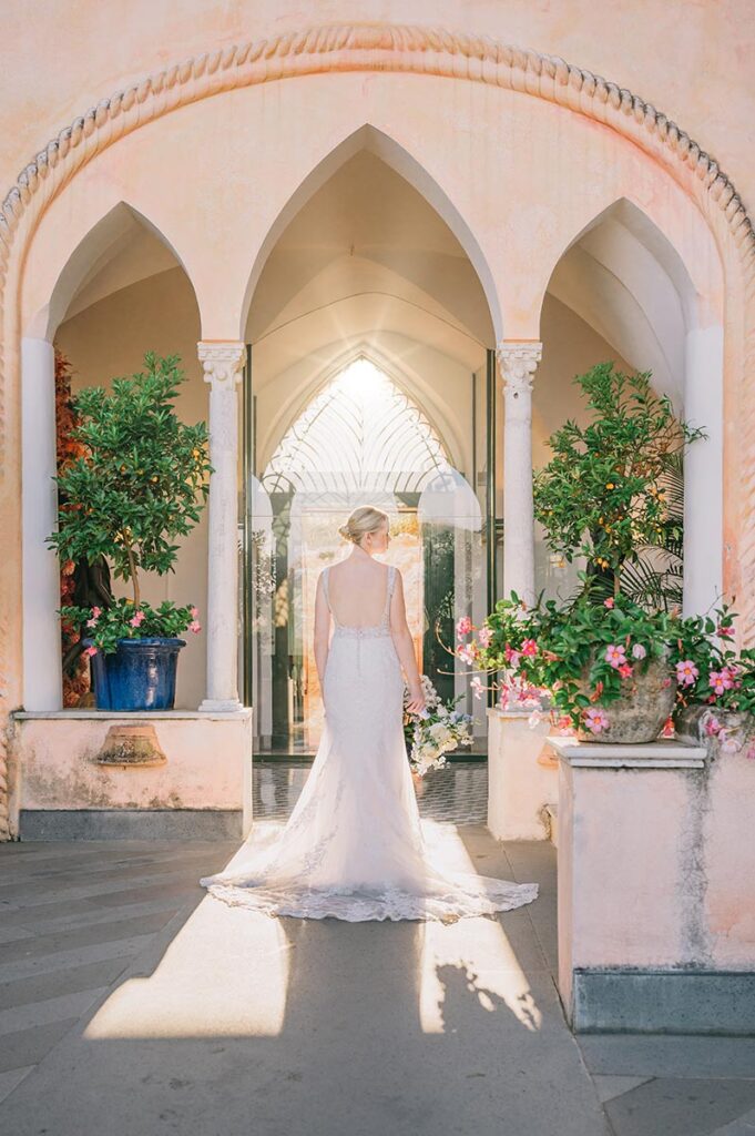 Bride in a Golden Light Archway at Palazzo Avino A bride in a stunning white gown stands in an elegant archway, bathed in golden light, during her Palazzo Avino wedding Ravello