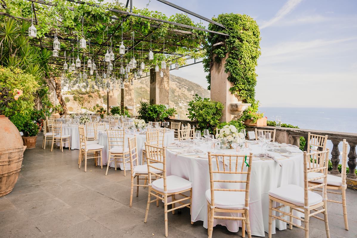 Wedding Reception Terrace with Sea View in Positano A scenic terrace set for a villa magia wedding positano, with tables under a pergola of vines and hanging lanterns overlooking the sea