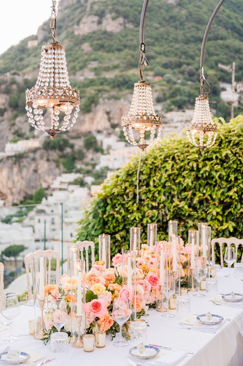 Luxury Wedding Reception with a View in Positano An elegant long table set for a glamorous villa magia wedding positano, with pink floral runners, tall candles, and crystal chandeliers
