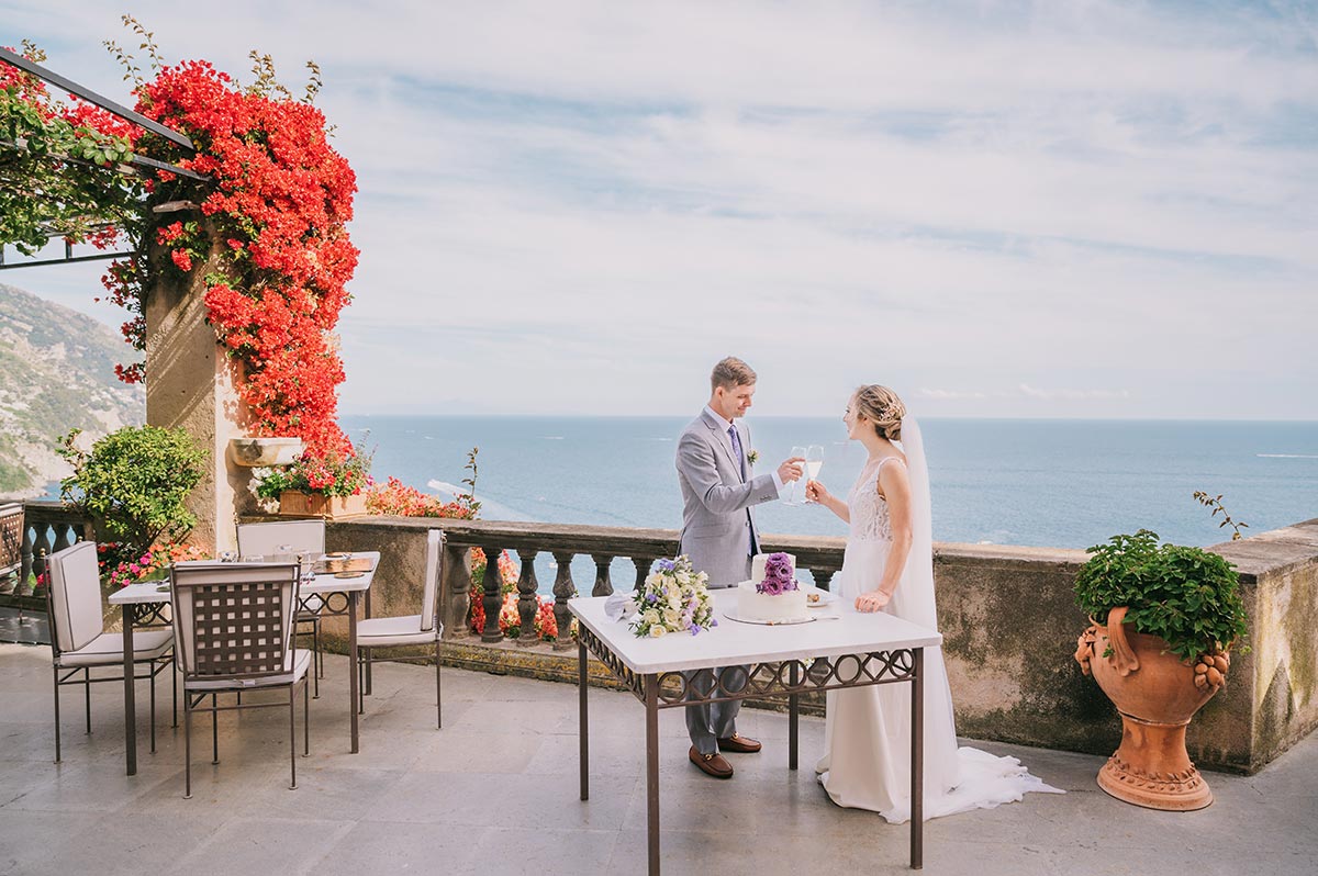 Romantic Wedding Toast with a View in Positano A bride and groom make a champagne toast on a scenic terrace during their intimate villa magia wedding positano, with the sea behind them