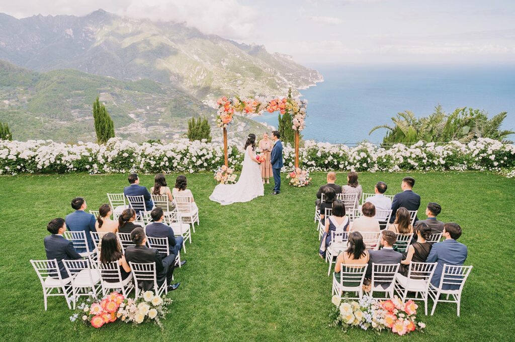 Outdoor wedding ceremony with sea view and floral arch, expertly organized by Amalfi Coast wedding planners