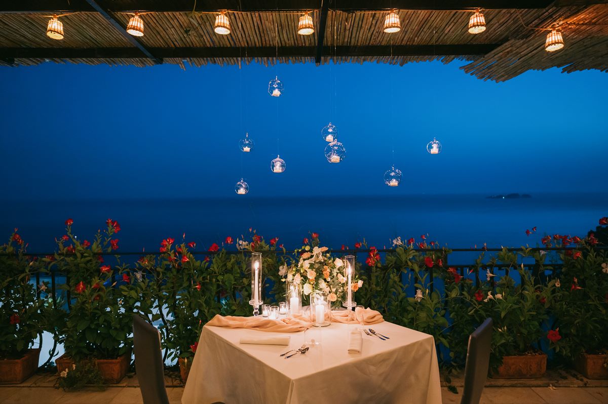 Magical Sweetheart Table with a View in Positano A romantic table for two set for a villa magia wedding positano, with floating glass candles glowing over the deep blue evening sea