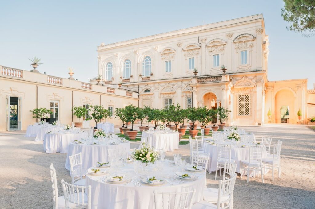 Elegant outdoor wedding reception at a historic Italian villa, featuring beautifully set tables with white decor, highlighting luxurious Italian wedding packages