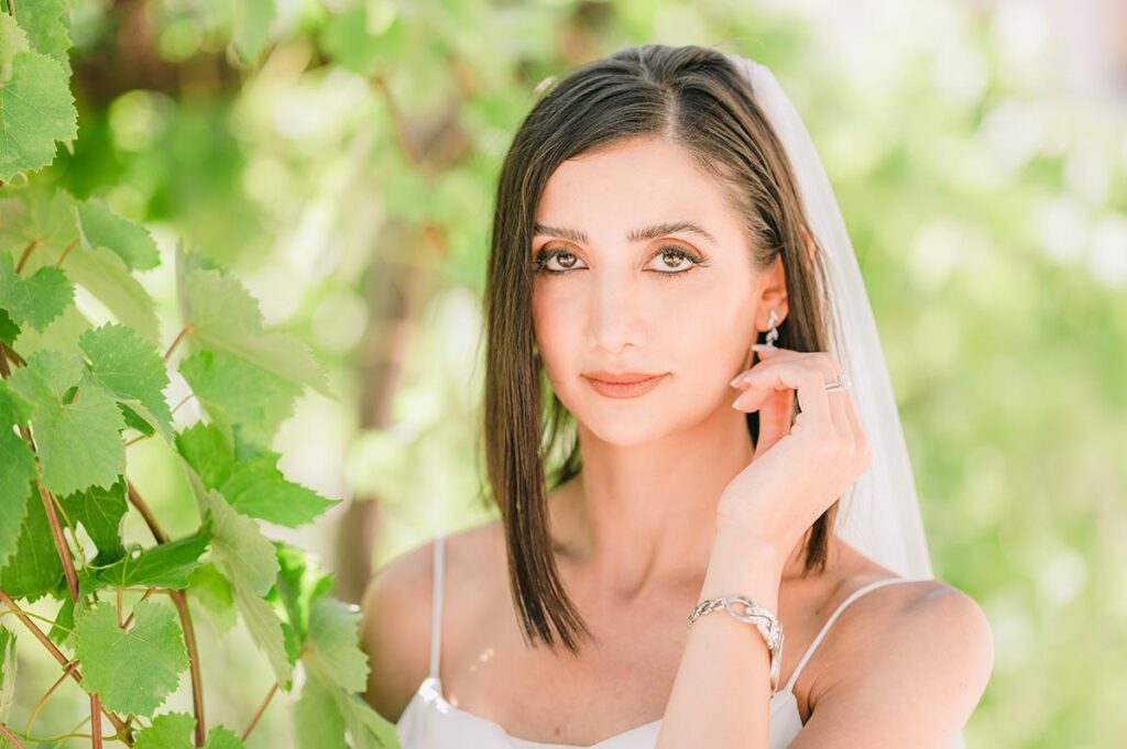 A bride poses elegantly among vineyard leaves at a Chianti wedding venue, exuding charm and grace