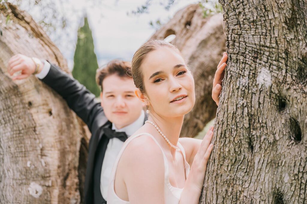 A couple poses romantically at a Chianti wedding venue, framed by ancient trees, blending elegance and nature