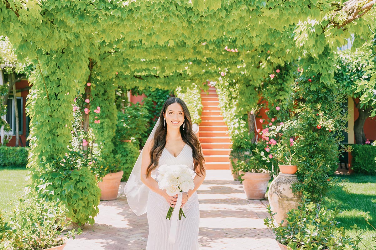 Bridal Portrait in the Gardens of Ravello A radiant bride holding a white rose bouquet in the gardens, moments before her Palazzo Confalone wedding Ravello
