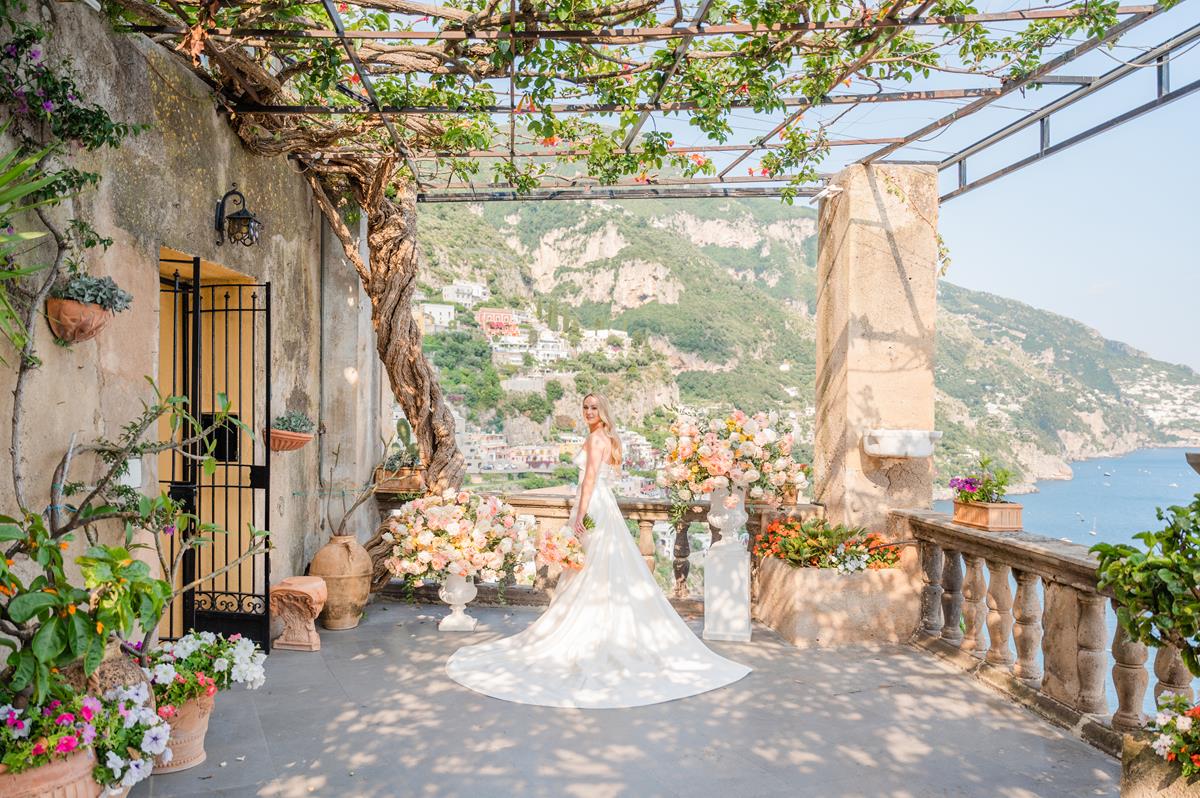 Epic Bridal Portrait on a Terrace in Positano A stunning bride poses on the scenic floral terrace during her villa magia wedding positano, overlooking the iconic coastline