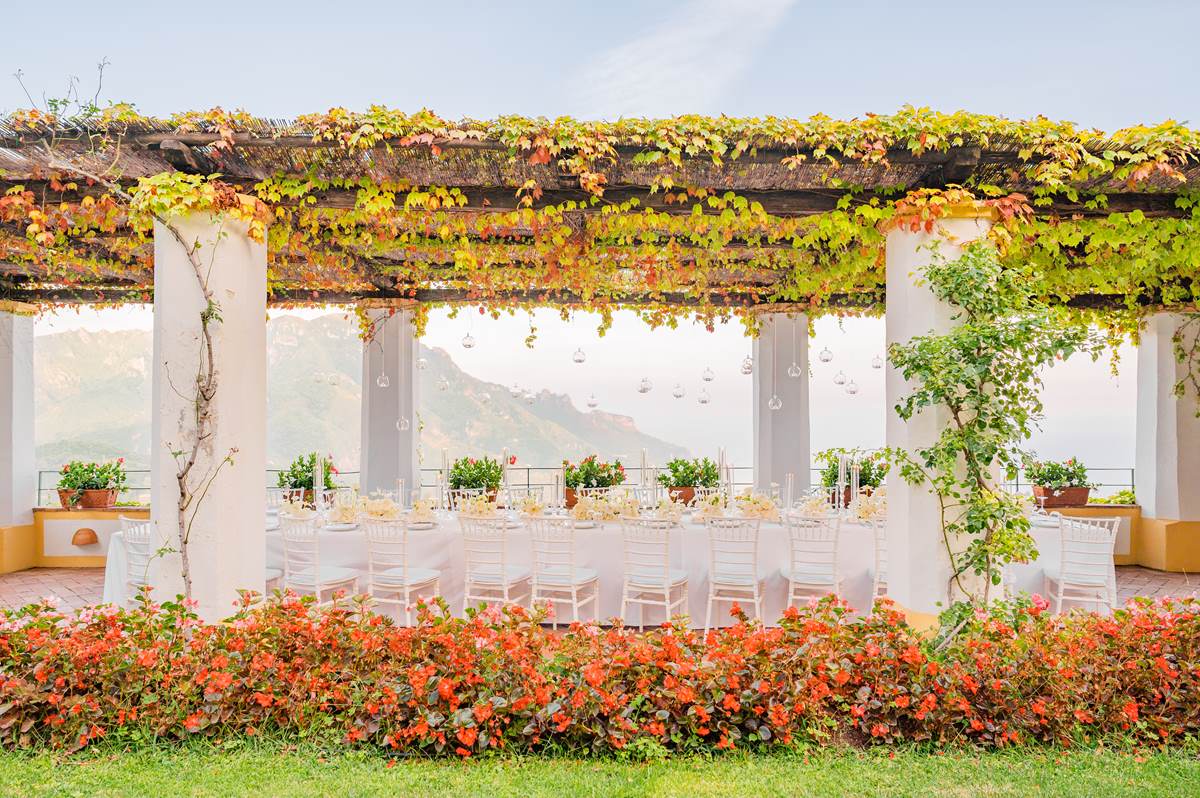 Romantic Wedding Reception on a Terrace An elegant reception table under a pergola with autumn leaves, the perfect setting for a Palazzo Confalone wedding Ravello
