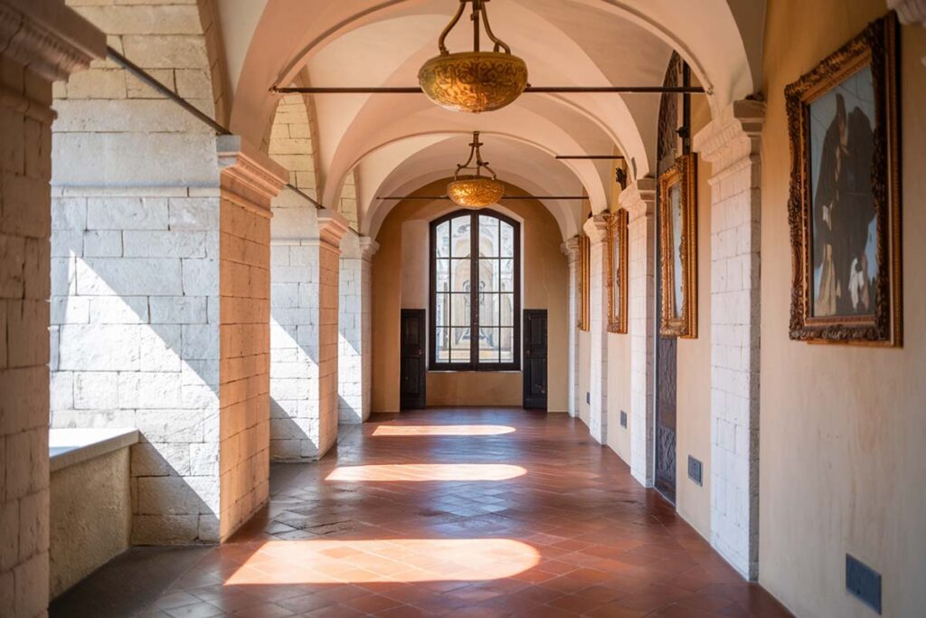 Sunlit corridor of a historic Italian villa with arched ceilings and elegant decor