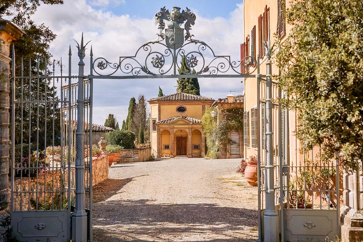 A grand entrance gate leading to a historic Chianti wedding venue, featuring a charming villa with classic Tuscan architecture