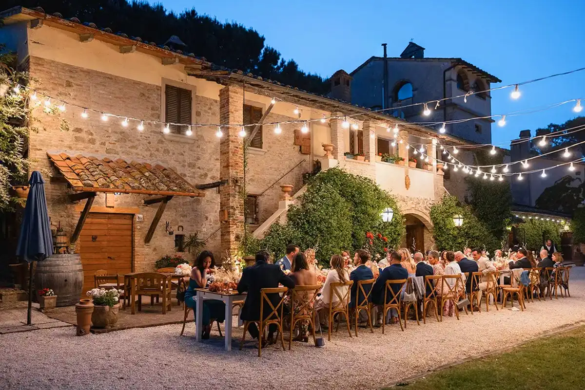 A romantic outdoor wedding reception at a Chianti wedding venue, with string lights, rustic charm, and guests dining under the evening sky