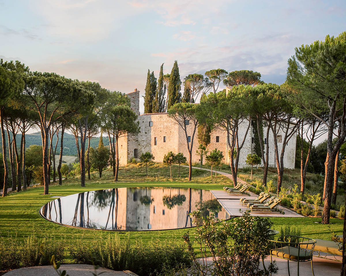 A stunning medieval castle in the Italian countryside, surrounded by lush greenery and a reflecting pool, ideal for an unforgettable wedding planned with expert guidance