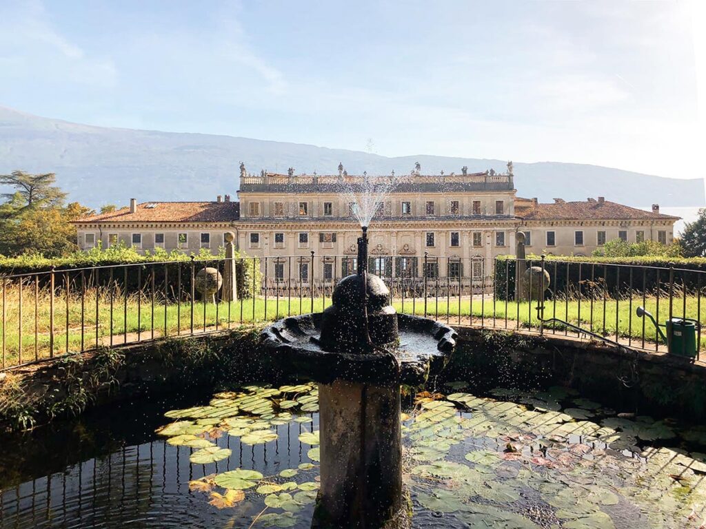 A charming Lake Garda wedding venue with a classical fountain surrounded by lush gardens and an elegant historic villa