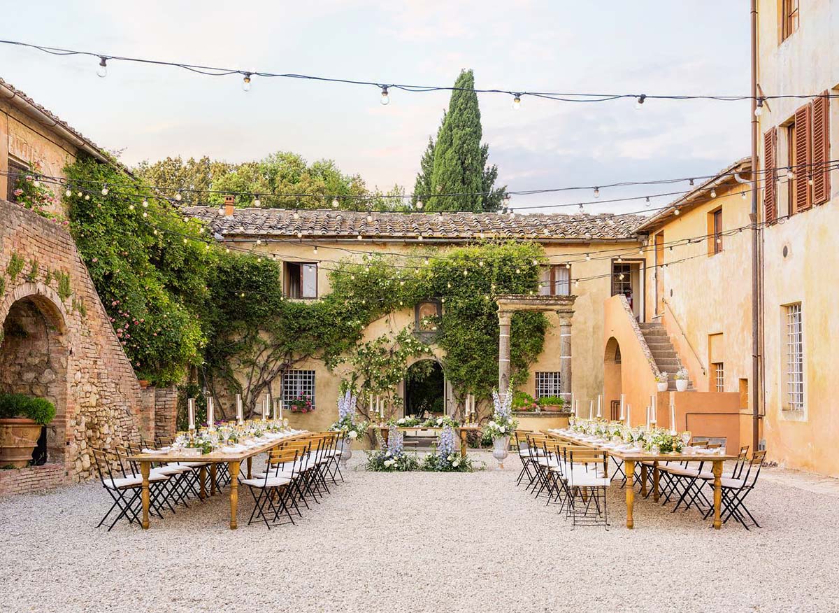 A charming Chianti wedding venue with a rustic courtyard, elegantly set for an outdoor reception with string lights and floral decor