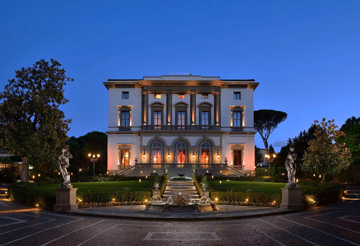 A luxurious Florence wedding venue in a historic villa, beautifully illuminated at dusk with elegant gardens and fountains
